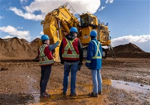 Three Fort Hills employees standing in front of the first PC9000, Komatsu's largest hydraulic shovel commercially available in the world, which was assembled at our Fort Hills mine in March/April 2025 by SMS Equipment. 