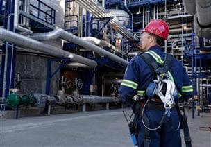 Un travailleur en action pendant son quart de travail à la plateforme 20 de MacKay River. Il porte un casque de sécurité, des lunettes de sécurité, des bouchons d'oreille, des gants et une combinaison.