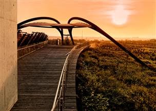 The Wapisiw Lookout walkway and observation deck at Suncor’s Base Plant site, with the sun setting in the background.