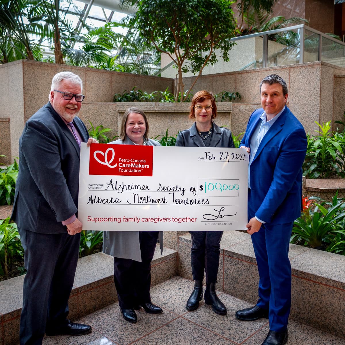 Four people standing holding a large cheque