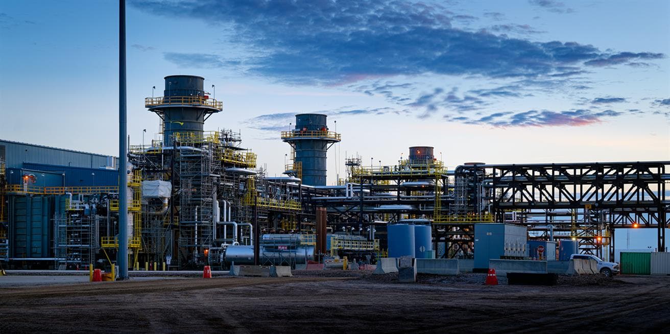 Four towers of the Cogeneration facilities at Suncor's Firebag in situ oil sands operation in northern Alberta, at dusk against a blue evening sky.