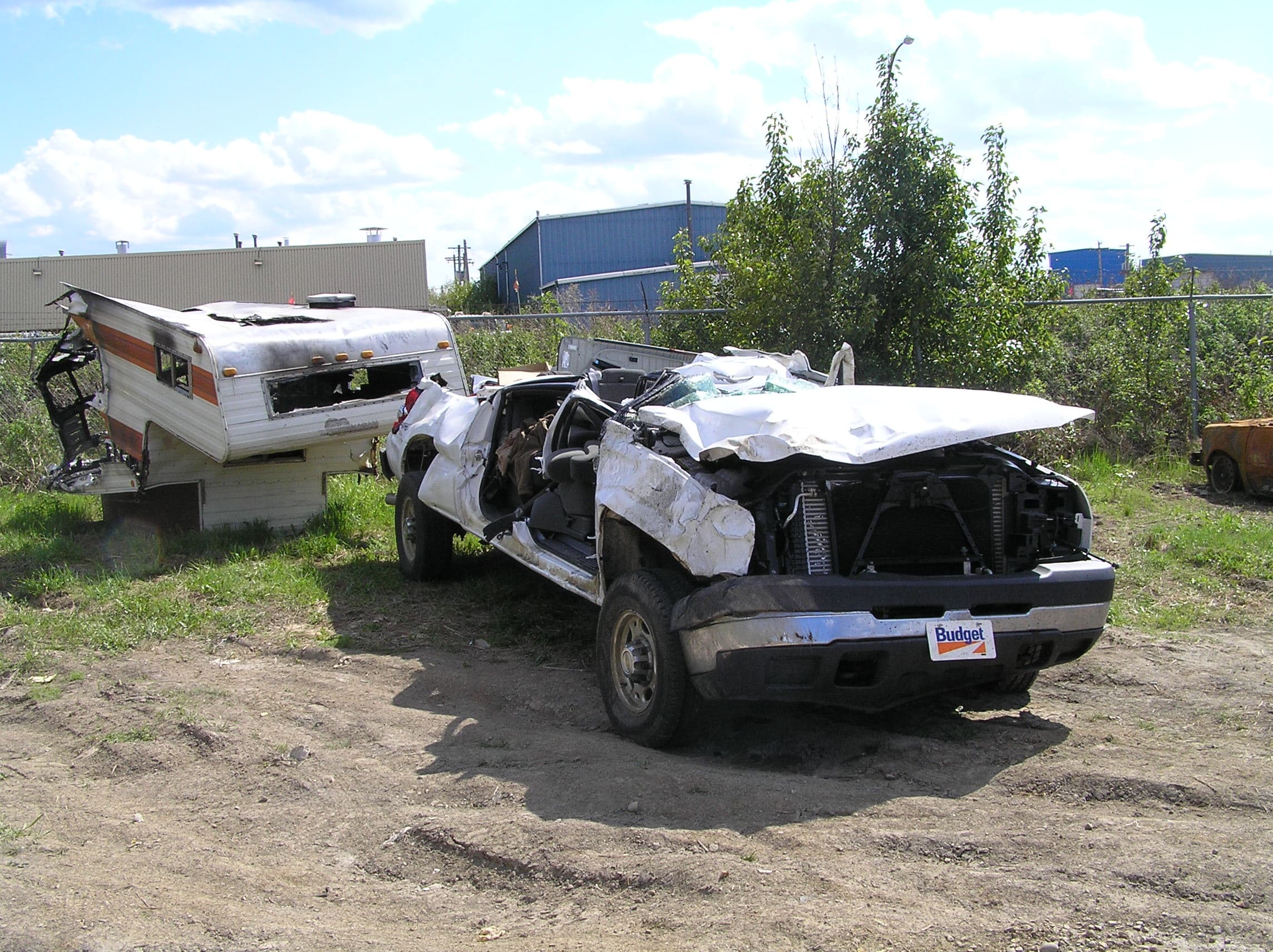 Un camion blanc écrasé et déformé. Le toit et les vitres du camion sont brisés.