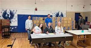 Suncor employees sitting at a table at the Adams 14 Thanksgiving food box distribution event.