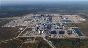 Vue aérienne d'un grand site d'activités in situ entouré d'une végétation abondante. L'installation comprend divers éléments de machinerie et équipements disposés dans la zone ouverte, avec des zones forestières clairement visibles autour du périmètre.