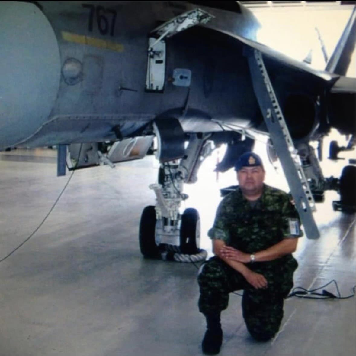 Greg in uniform in front of a fighter jet 