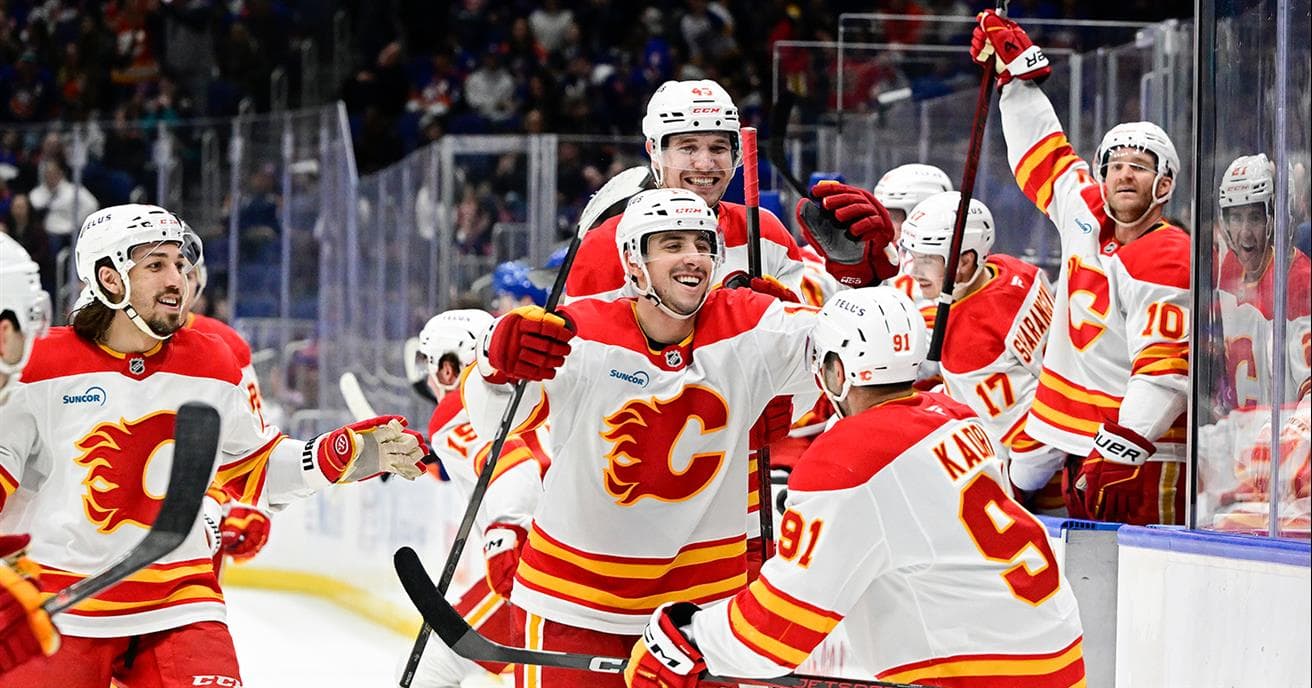 Des joueurs des Flames de Calgary célèbrent un but. Leurs chandails des Flames arborent un logo bleu de Suncor du côté droit de la poitrine.