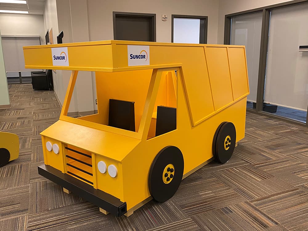A yellow children’s play structure in the shape of a heavy hauler.