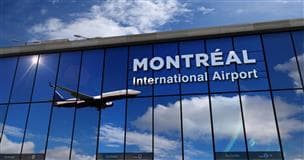 A view of the windows of the Montreal International Airport. In the reflection a plane is taking off.