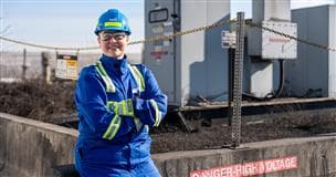 Lora Cardinal, employée autochtone, électricienne et formatrice en électricité à l'installation de l'usine de base, porte un ÉPI et se tient près des actifs à haute tension.