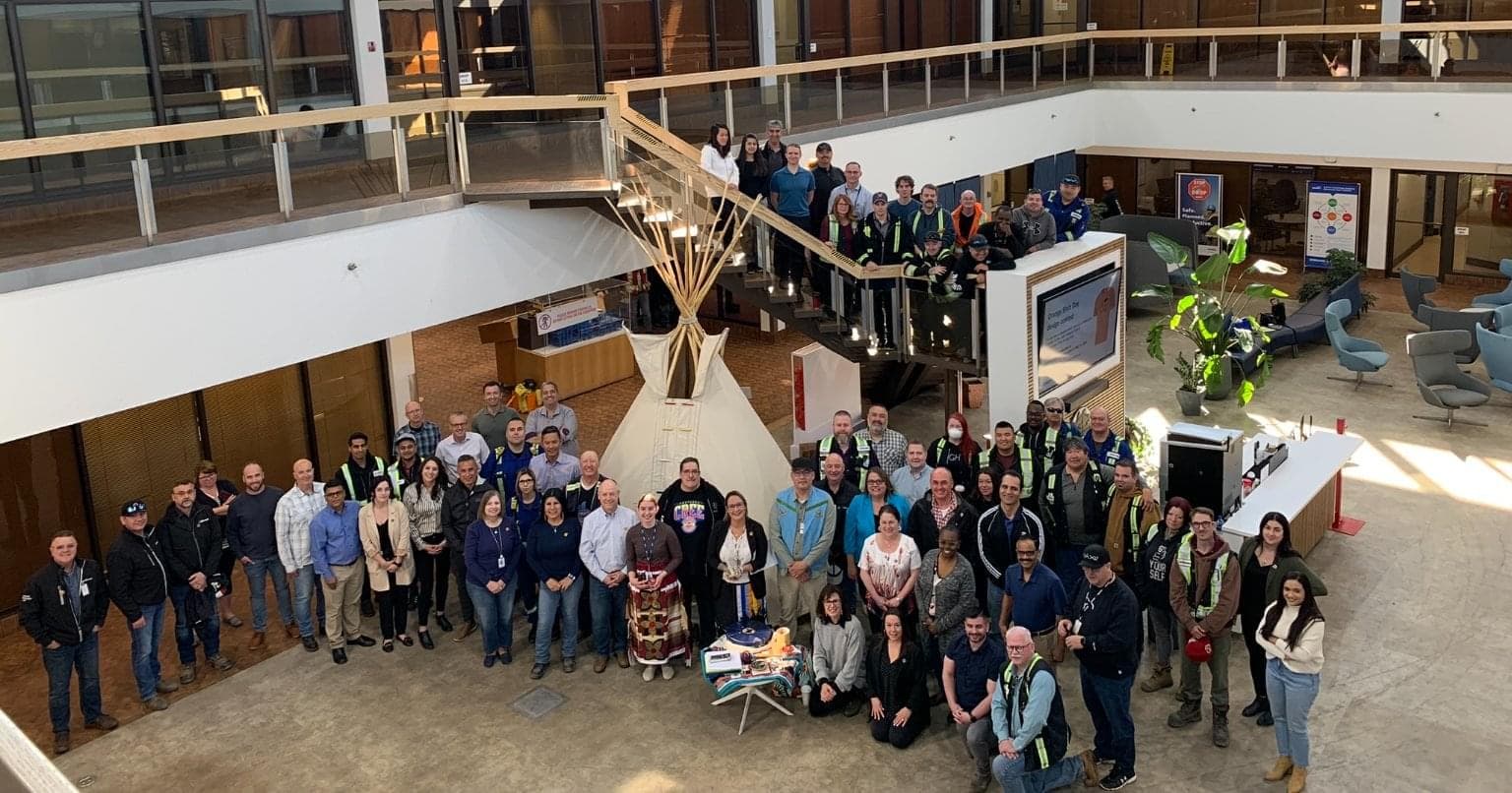 A group of employees gather around a teepee inside a building.