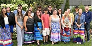 Members of Suncor’s Indigenous Youth Advisory Council stand together outdoors in a garden with several wearing colourful ribbon skirts.