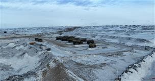 Équipement minier garé dans une mine de sables bitumineux en hiver. Il y a de la neige au sol.