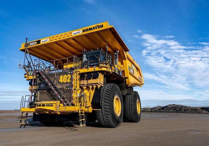 A close-up of a 400 tonne Komatsu 980E model haul truck with blue skies in the background.