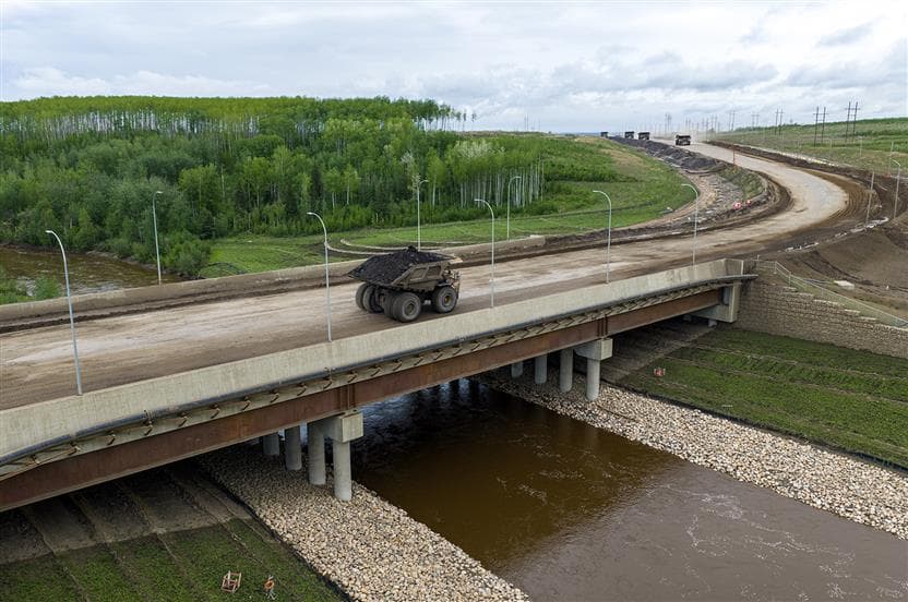 Haul trucks crossing the Mildred Lake Mine extension (MLX) bridge over the river at Suncor’s Syncrude site in Northern Alberta.