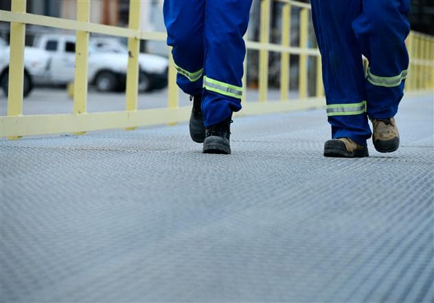 The picture shows the feet of two workers walking outside at the Montreal refinery.