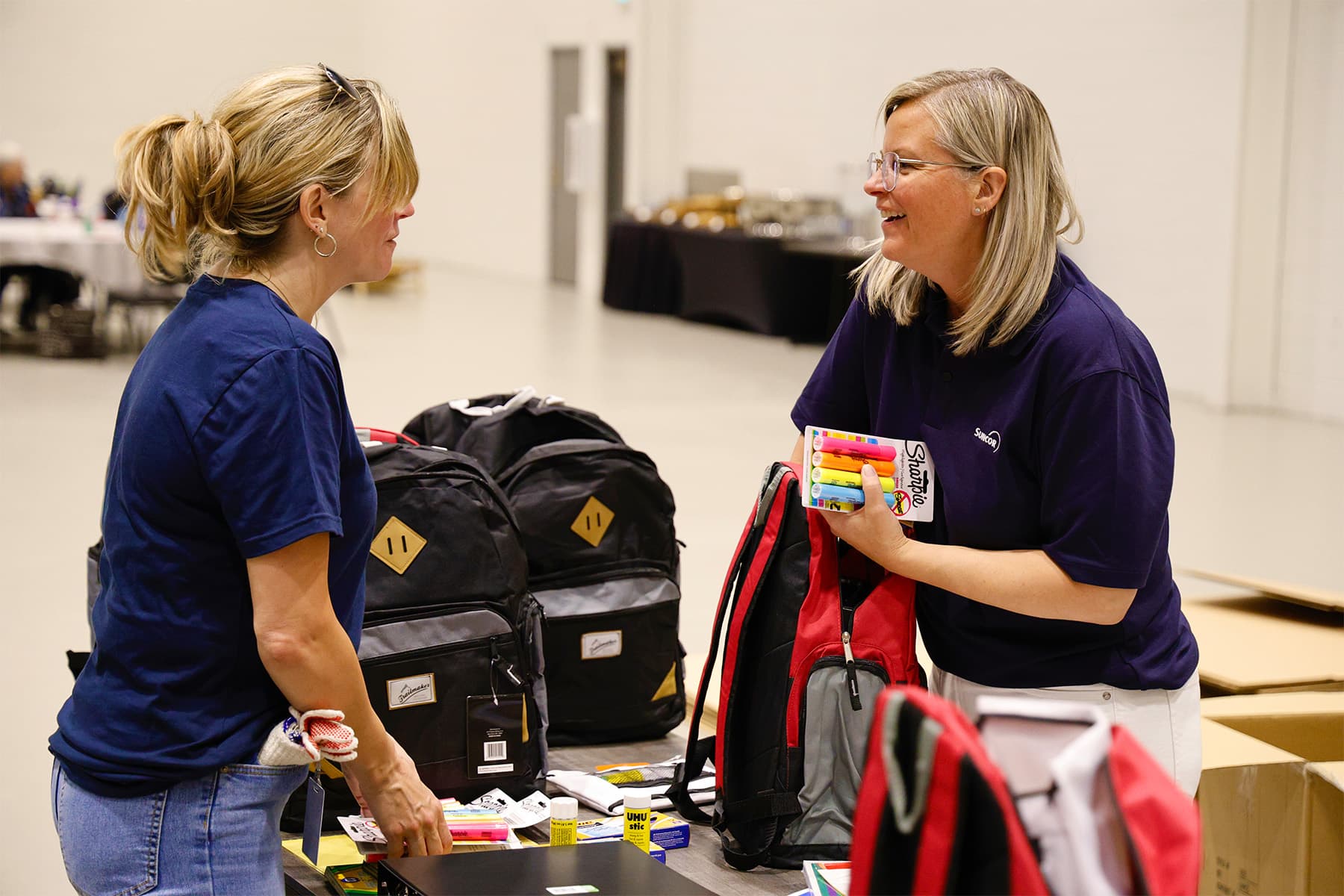 Two Suncor employees put school supplies in backpacks for kids.
