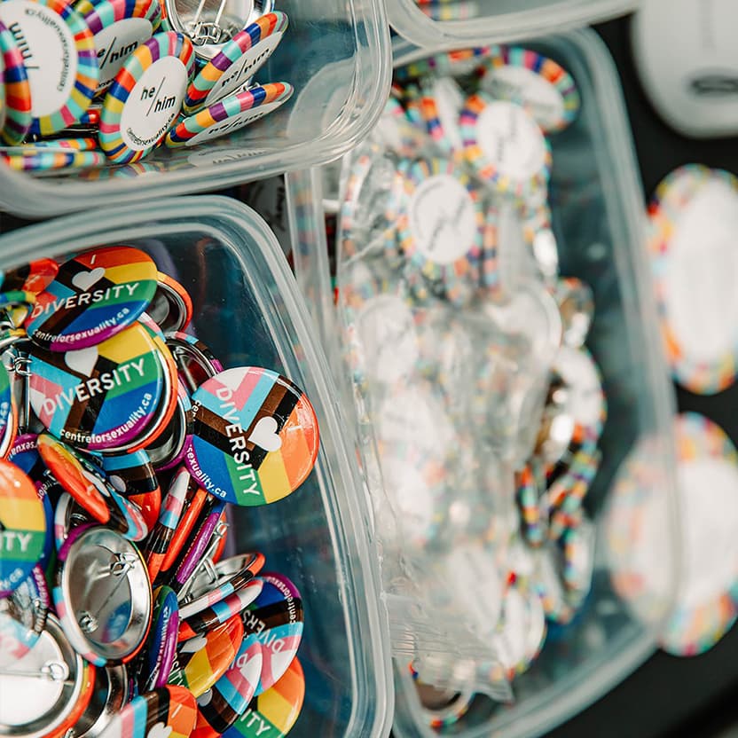 Suncor/ Pride "diversity" pins in bucket placed on a table.