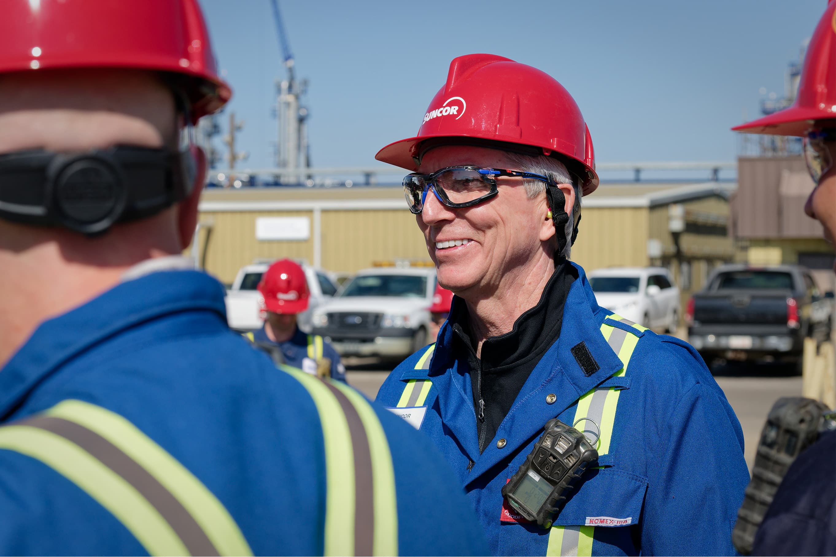 Rich Kruger, président et chef de la direction, qui parle avec des travailleurs pendant une visite de la raffinerie d'Edmonton durant une journée ensoleillée. Ils portent un casque de protection rouge, des lunettes de sécurité et une combinaison.