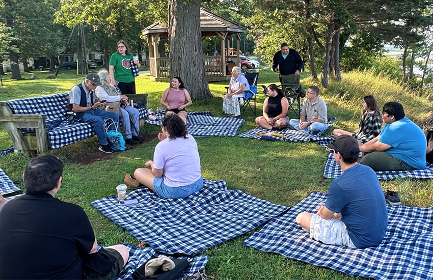 Des membres de l’Indigenous Youth Advisory Council de Suncor sont assis ensemble sur des couvertures dans une zone extérieure pendant le rassemblement annuel 2026 à Sarnia.